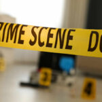 Yellow crime scene tape with evidence markers in a room