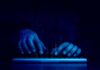 Hands typing on a keyboard with a digital binary background