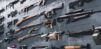 Person holding an AK-47 rifle with a scope