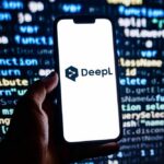 A hand holding a smartphone displaying the DeepL logo against a programming code background