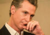 Close-up of a man in a suit with a thoughtful expression, hand on chin