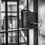 Guantanamo’s Empty Beds: The Untold Story Close-up of a jail cell lock with a key hanging