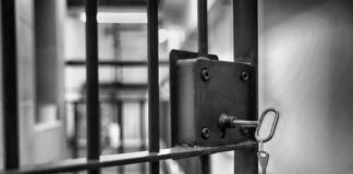 Close-up of a jail cell lock with a key hanging