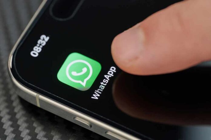 Finger tapping the WhatsApp icon on a smartphone screen