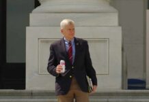 man in blazer holding a soda can on building steps
