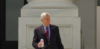 man in blazer holding a soda can on building steps