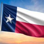 Texas state flag waving against a sunset sky