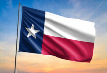 Texas state flag waving against a sunset sky