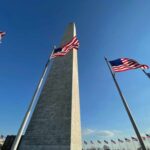 Washington Monument surrounded by American flags under a clear blue sky