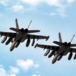 Two military fighter jets flying in formation against a blue sky