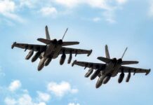 Shocking Jet Collision – Public Demands Answers! Two military fighter jets flying in formation against a blue sky