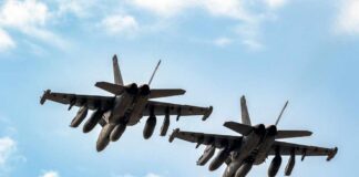 Two military fighter jets flying in formation against a blue sky