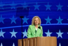 Florida Democrats SLAM Schultz’s ‘Politically Convenient’ Bid A hand placing a ballot into a ballot box with an American flag in the background