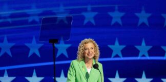 Florida Democrats SLAM Schultz’s ‘Politically Convenient’ Bid A hand placing a ballot into a ballot box with an American flag in the background
