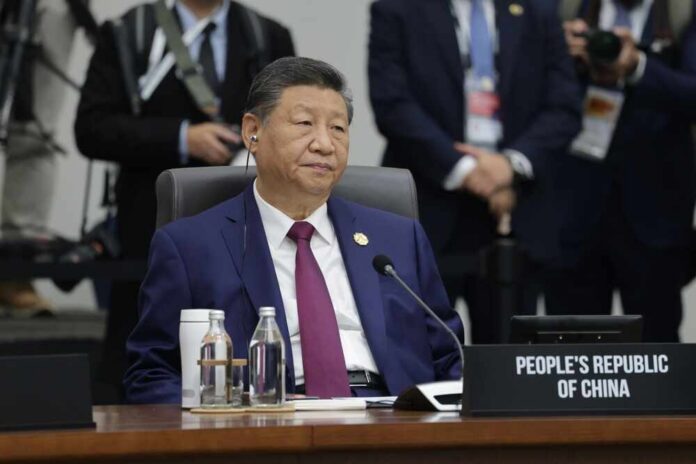 A seated leader at a conference table with a nameplate indicating the People's Republic of China