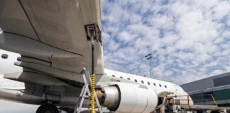 An airplane being fueled at an airport with visible ground support equipment
