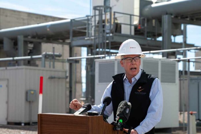 Man in a hard hat speaking at a podium in an industrial setting