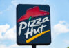 AI Mandate Wreaks Havoc on Pizza Giant restaurant sign with red roof logo against blue sky