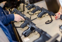 A customer examining handguns at a firearms shop display