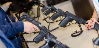 A customer examining handguns at a firearms shop display