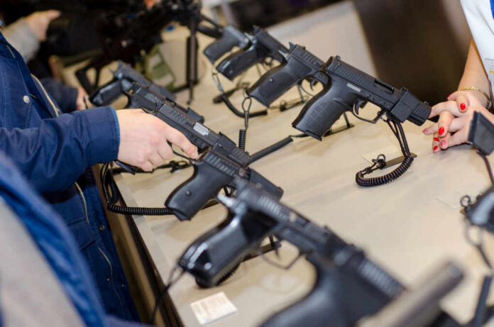 A customer examining handguns at a firearms shop display