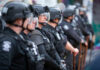 Belfast Erupts — Water Cannons Unleashed Line of riot police in tactical gear standing ready for crowd control