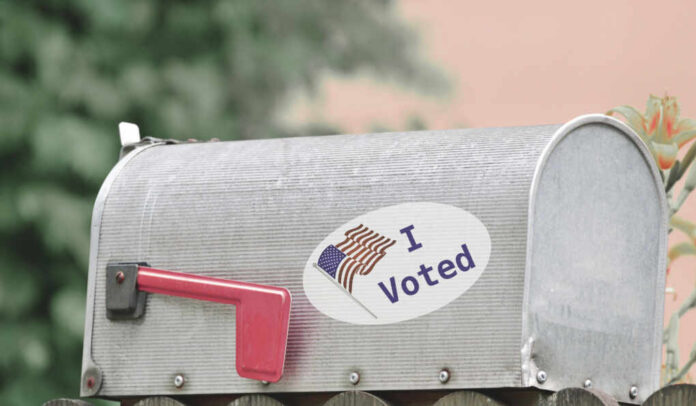 A metal mailbox with an I Voted sticker and an American flag design
