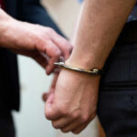A close-up of a person being handcuffed by an officer