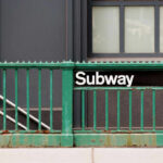 Subway entrance with a green railing and a sign reading Subway