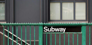 Subway entrance with a green railing and a sign reading Subway