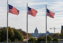 Three American flags waving in front of the Capitol building in Washington D.C.
