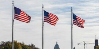 Three American flags waving in front of the Capitol building in Washington D.C.