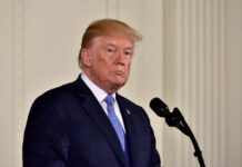 Trump Slams California Count — Demands Federal Probe A political figure standing at a microphone with a serious expression