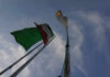 Two flags on a flagpole against a blue sky with clouds