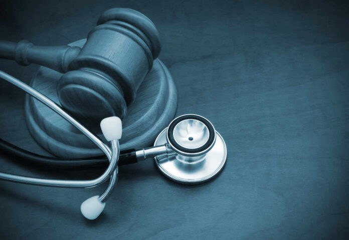 A wooden gavel next to a stethoscope on a dark surface