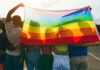 Group of people holding a rainbow flag during a pride celebration