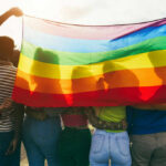 Pride Flags Confront FIFA’s ‘Neutrality’ Group of people holding a rainbow flag during a pride celebration