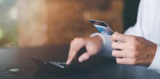 $26M Funding Push: AI Bidding War Hits TikTok, eBay Person holding a credit card while using a calculator at a desk