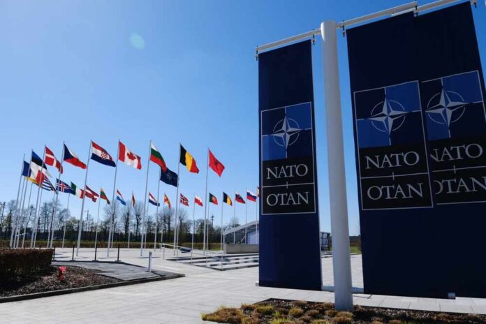 The,National,Flags,Of,Countries,Member,Of,The,Nato,Fly Flags of various nations displayed outside NATO headquarters under a clear blue sky