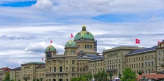 Swiss flag waving in front of Lake Lucerne with a city skyline in the background