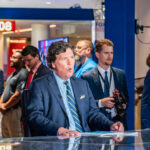 News anchor speaking in a television studio with crew members in the background