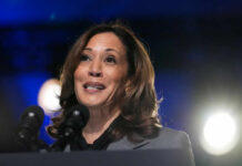 A female politician speaking at a podium with microphones in front of her