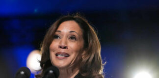 A female politician speaking at a podium with microphones in front of her