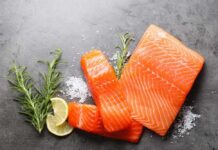 Fresh salmon fillets with lemon and herbs on a dark surface