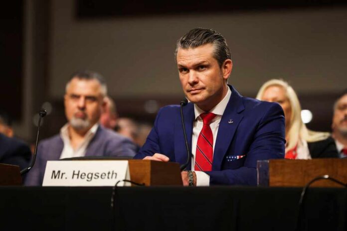 Washington,-,January,14,2025:,Pete,Hegseth,,Secretary,Of,Defense A man in a blue suit and red tie sitting at a hearing table with a nameplate