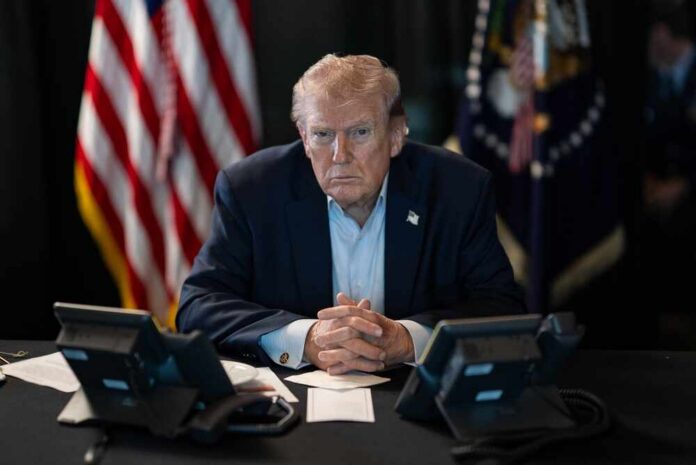 President,Donald,J.,Trump,Oversees,Operation,Epic,Fury,At,Mar-a-lago, A serious-looking man seated at a table with phones and an American flag in the background