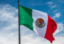 Stadium Routes CHOKED — Chaos Looms Waving Mexican flag against a blue sky
