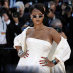 A celebrity posing on the red carpet at an event, surrounded by photographers