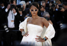 A celebrity posing on the red carpet at an event, surrounded by photographers