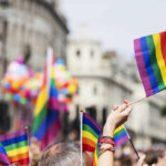 Crowd holding rainbow flags at a Pride parade